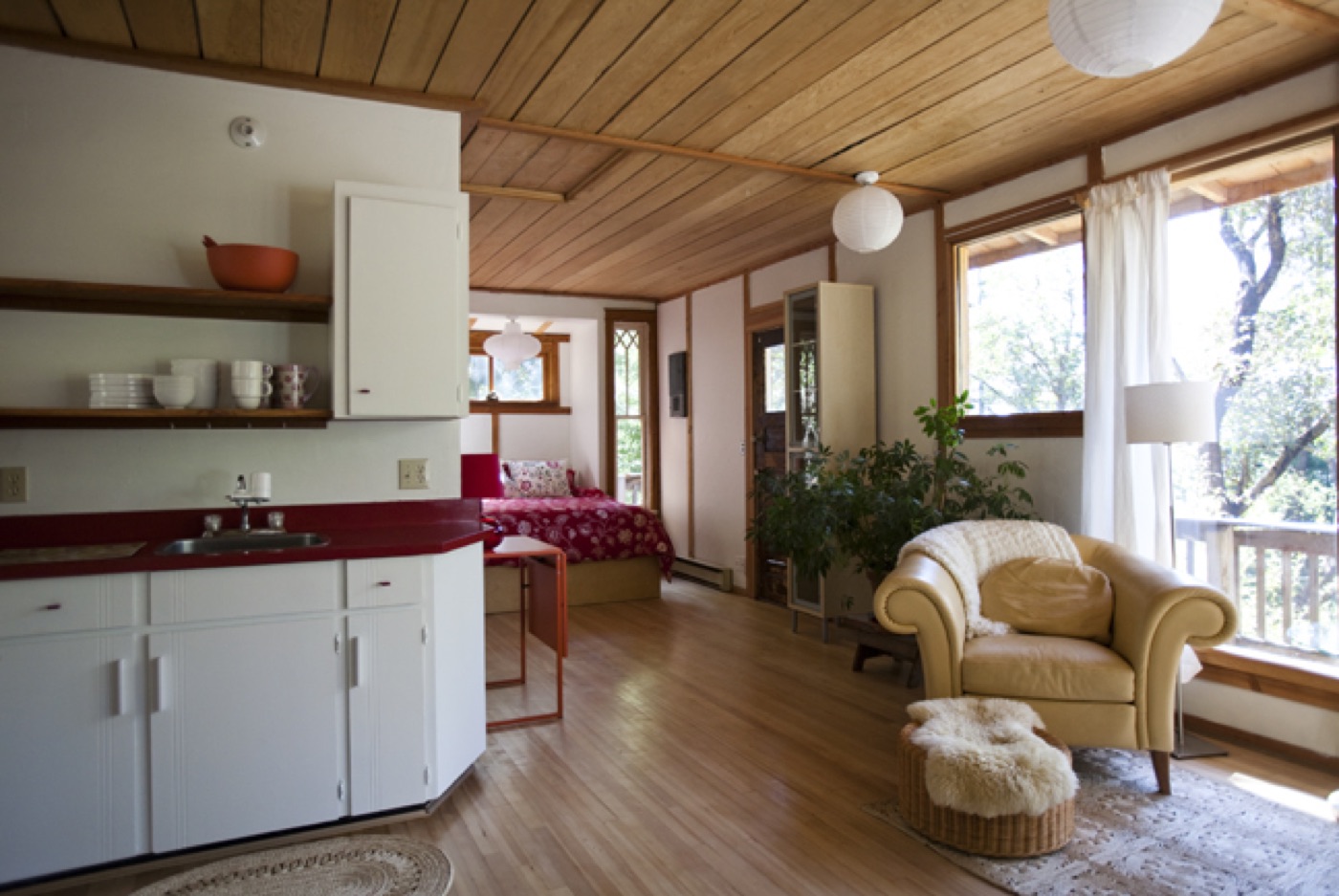 One warm open room: kitchenette, bed, and reading corner