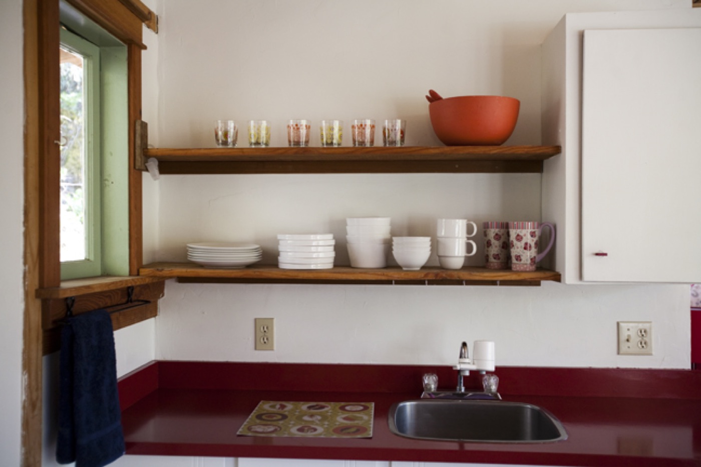 Kitchenette shelves — dishes, mugs, and the big orange bowl
